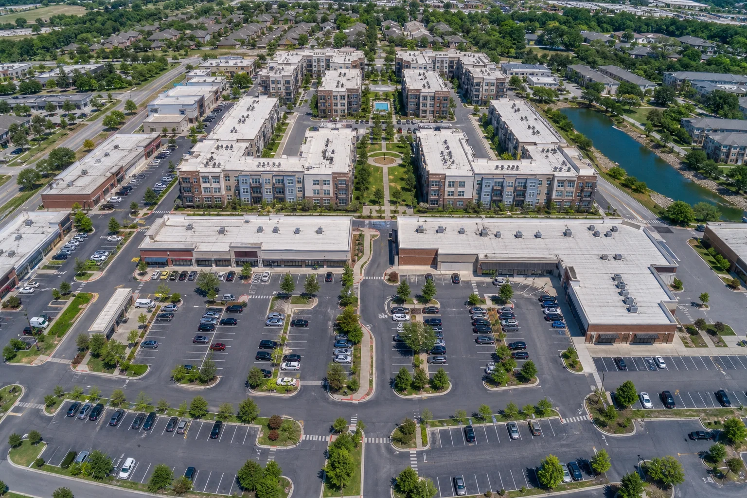 Aerial drone view of a mixed-use commercial real estate development with mid-rise apartment buildings and retail properties in a planned urban layout, daytime